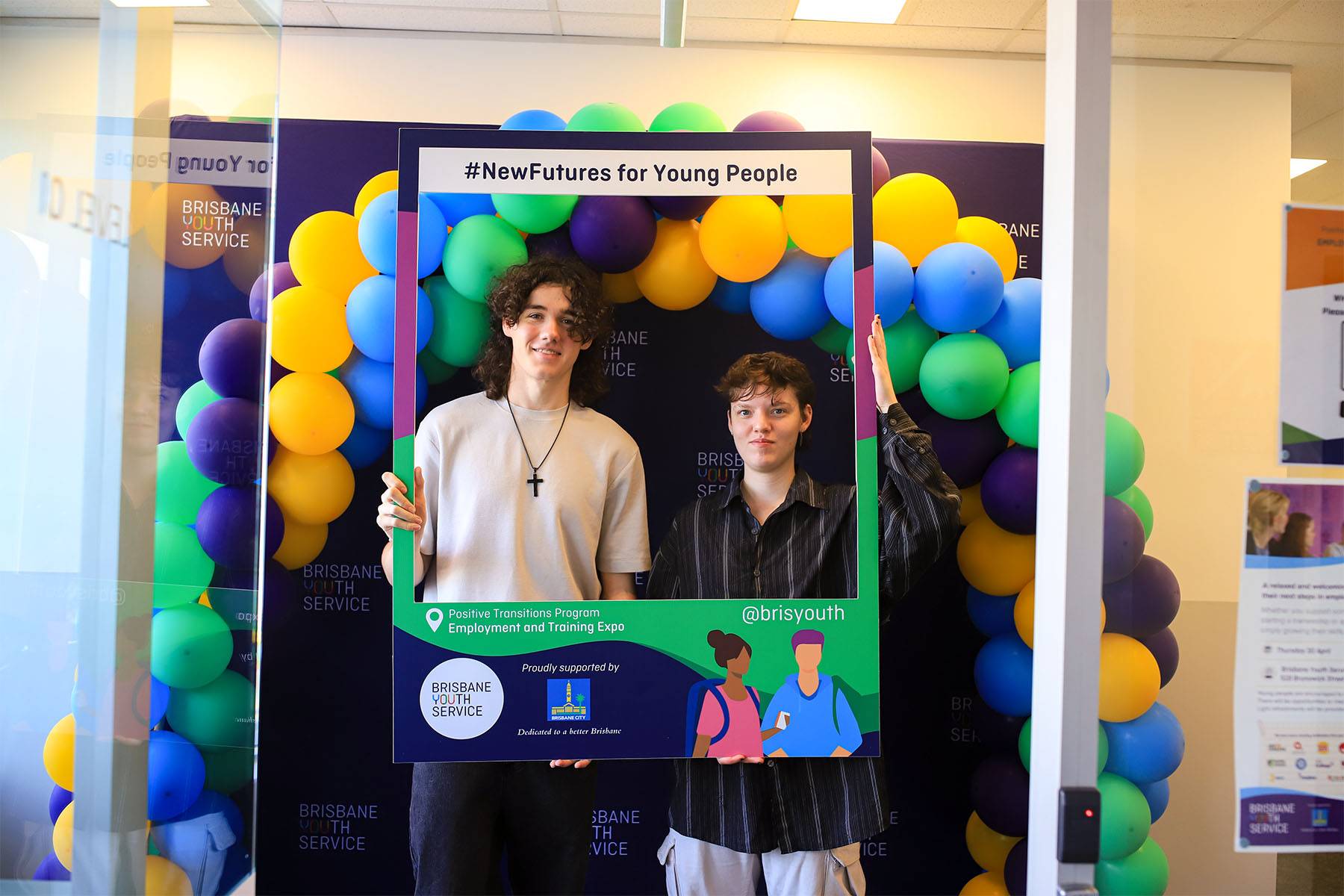 Young people at Positive Transitions Expo, holding corflute New Futures for Young People, surrounded by balloons